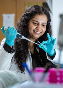 Shristi Singh uses a syringe on a pippette in a lab.